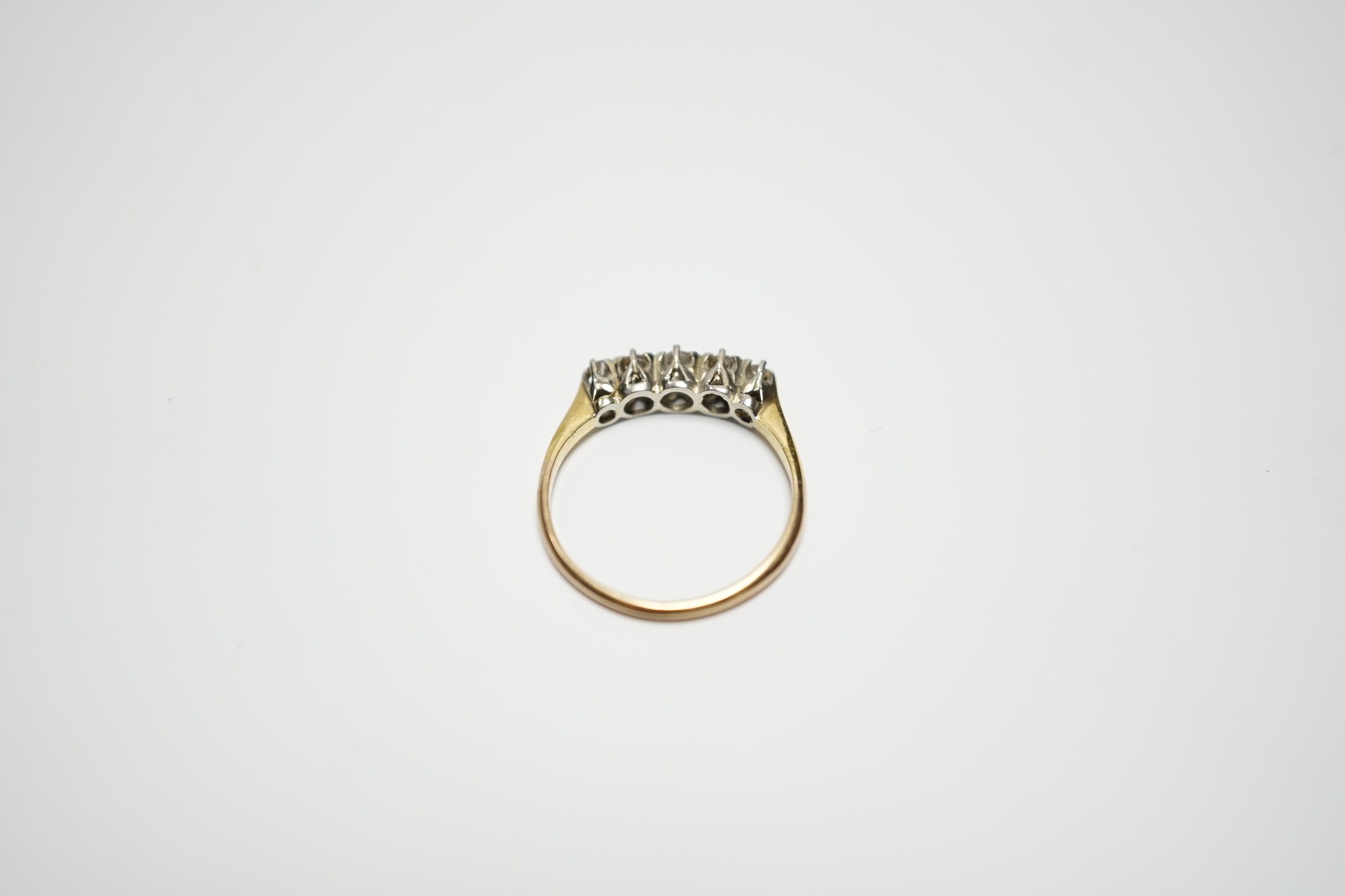 A yellow metal and graduated five stone diamond set half hoop ring, size M, gross weight 2 grams.